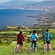 4 bicyclists pause on a grassy hillside with a wide view of a coastline